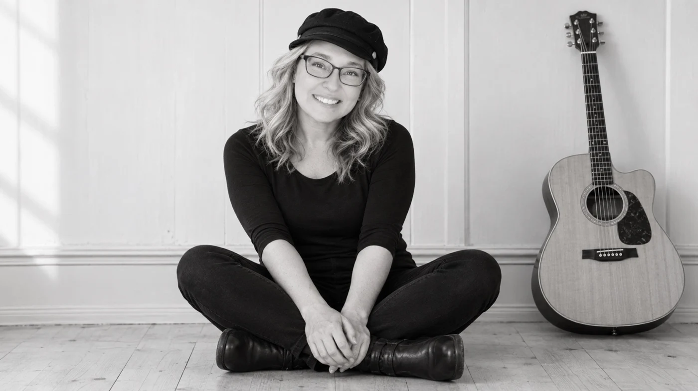 Amy Matthew seated beside an acoustic guitar